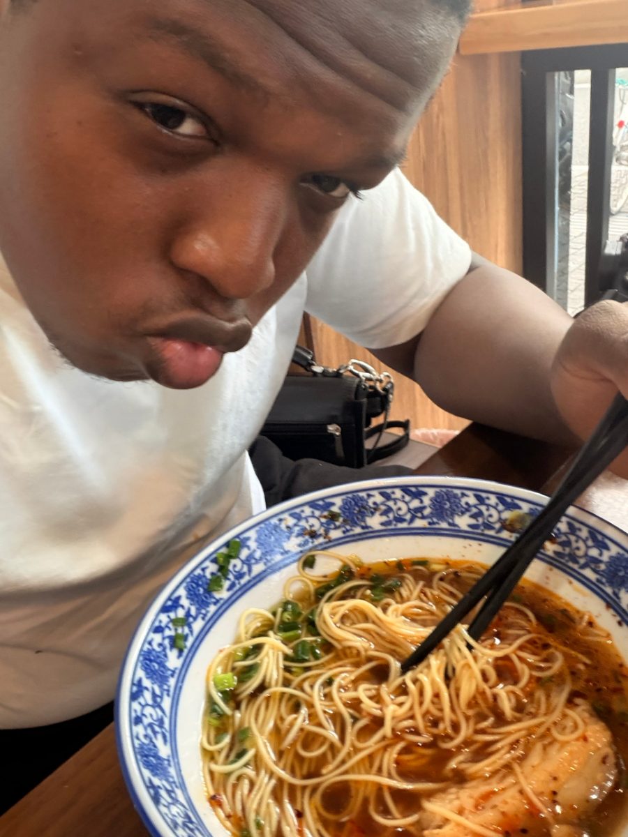 Pamimo pulling a face over a blue and white bowl of spicy noodles