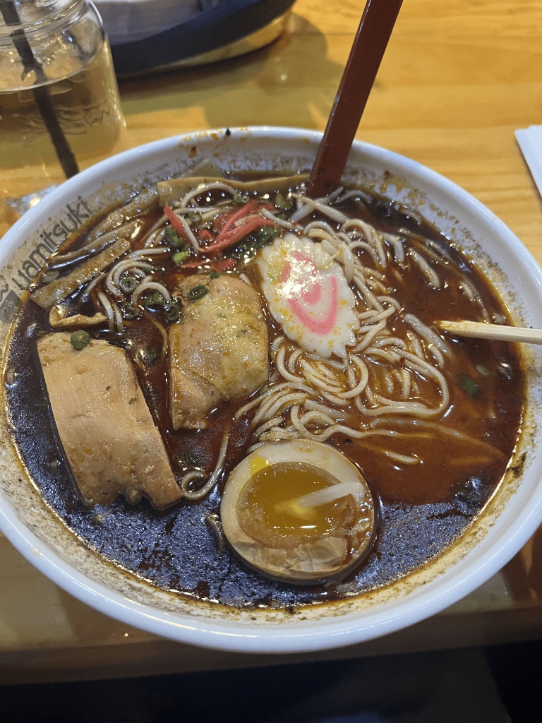 A bowl of spicy ramen with chashu, a soft egg and fish cake